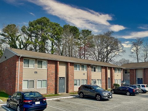 an apartment building with cars parked in a parking lot