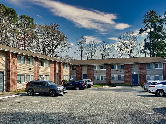 an apartment building with cars parked in a parking lot