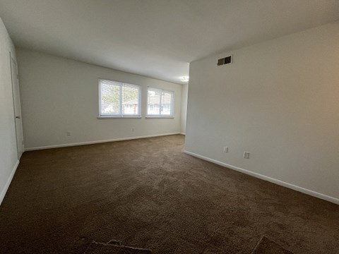 an empty living room with carpet and a window