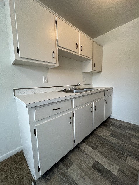 an empty kitchen with white cabinets and a sink