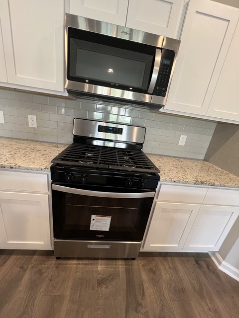 a kitchen with white cabinets and a stove and a microwave