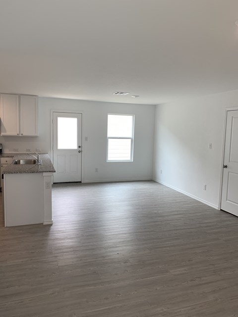 an empty kitchen and living room with white walls and wood floors