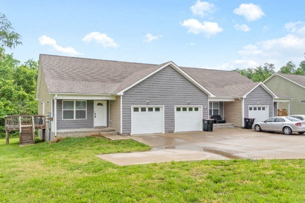 a gray house with two garage doors and a driveway