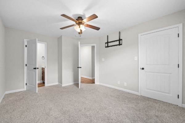 an empty living room with a ceiling fan and white doors