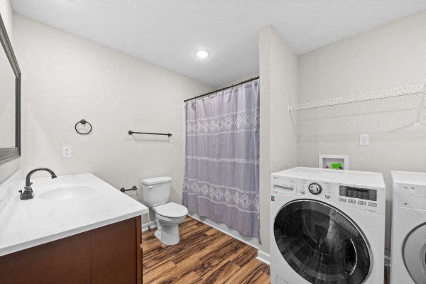 a white bathroom with a washing machine and a toilet
