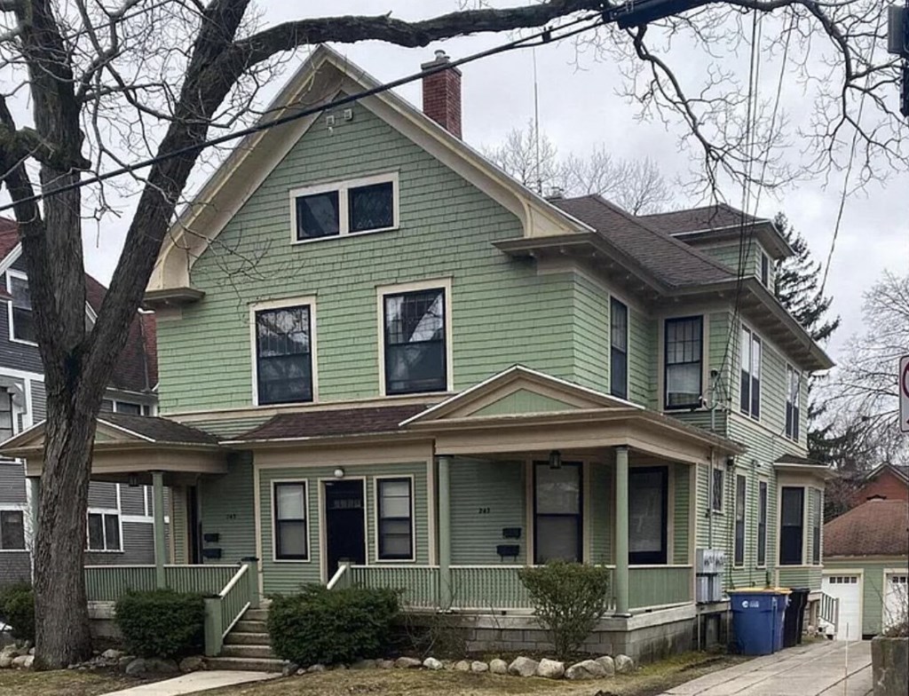 a green house with a tree in front of it