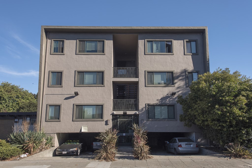 a tall apartment building with cars parked in front of it