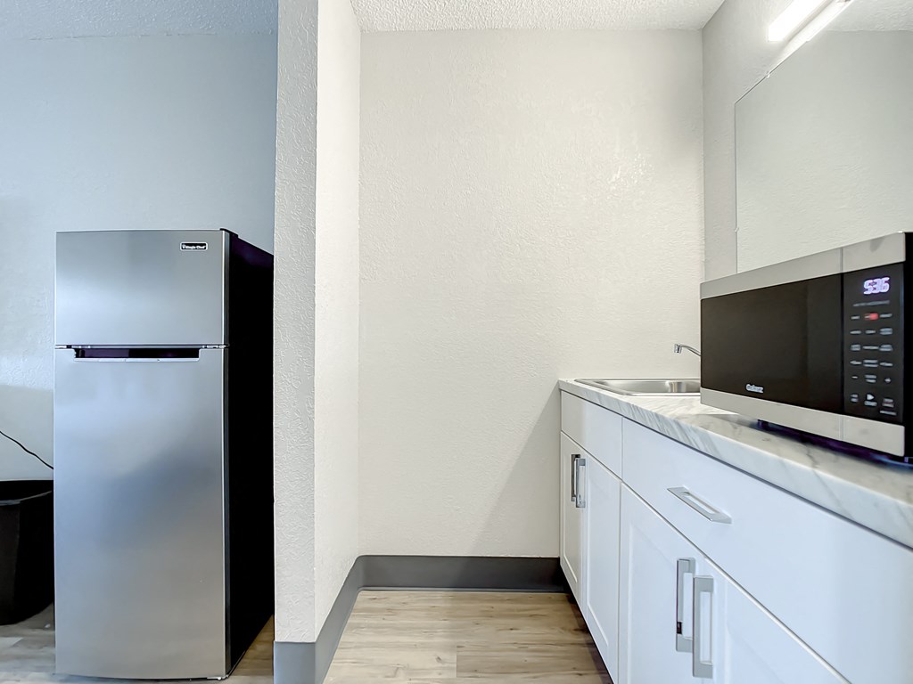 a kitchen with a refrigerator and a microwave and a sink