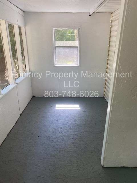A room with a window and a phone number for a property management company.