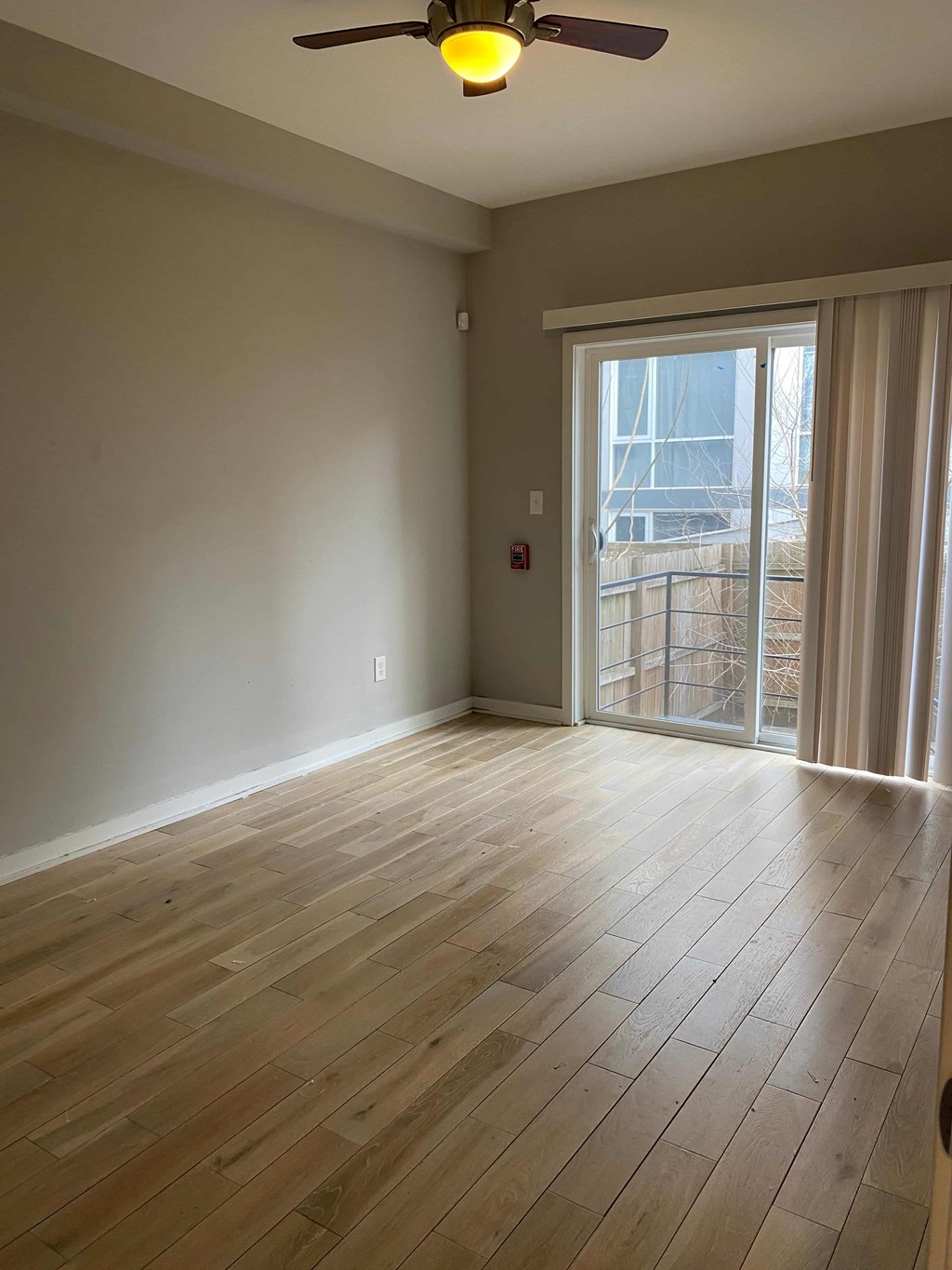 an empty living room with wood floors and a sliding glass door
