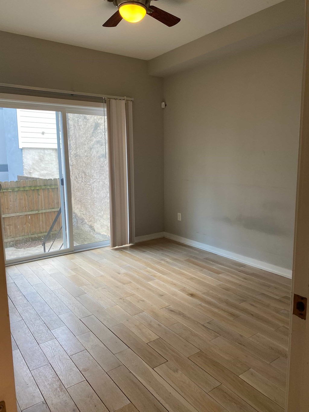 an empty living room with wood floors and a sliding glass door