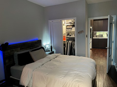 a bedroom with a bed and a closet with a blue light in it