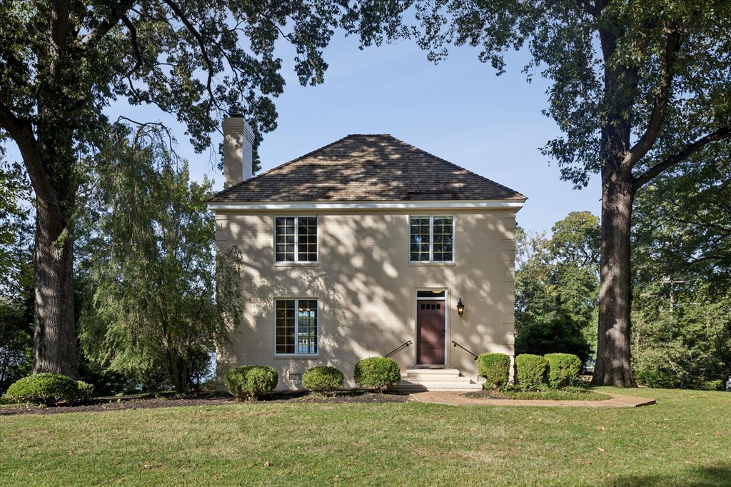 A small house with a brown door is surrounded by trees.