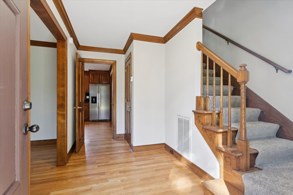 A hallway with a staircase and a door on the left.