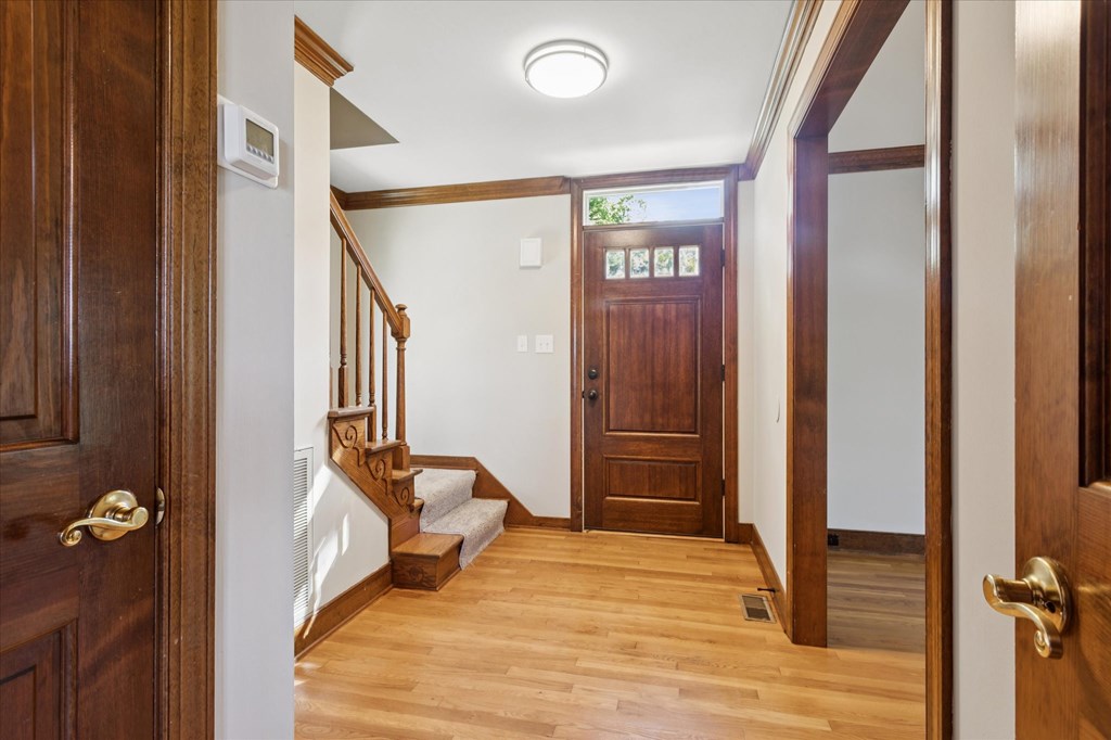 A hallway with a wooden floor and a staircase with a white railing.