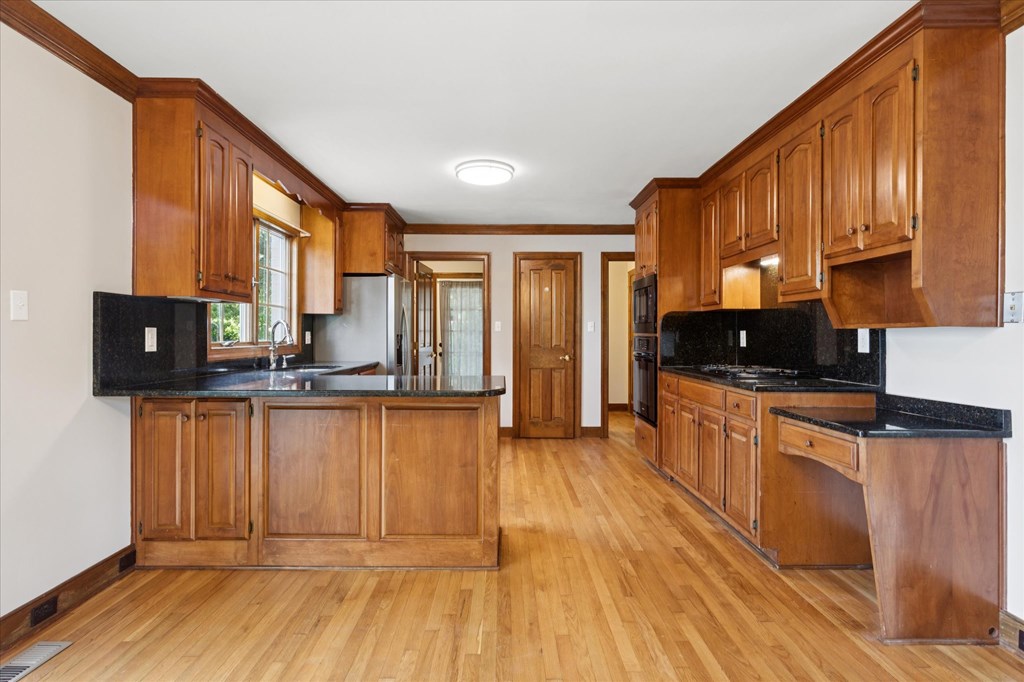 A kitchen with wooden cabinets and black countertops.