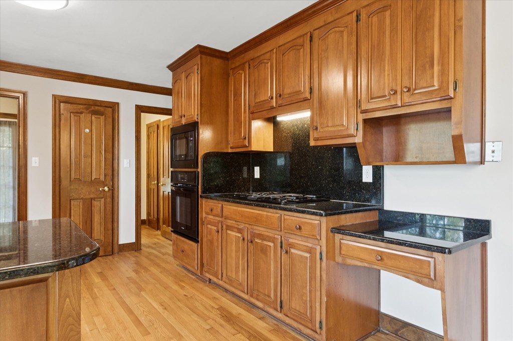 A kitchen with wooden cabinets and black countertops.