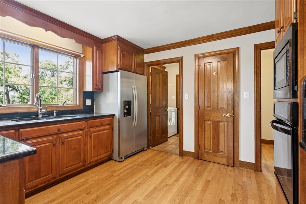 A kitchen with wooden cabinets and a stainless steel refrigerator.