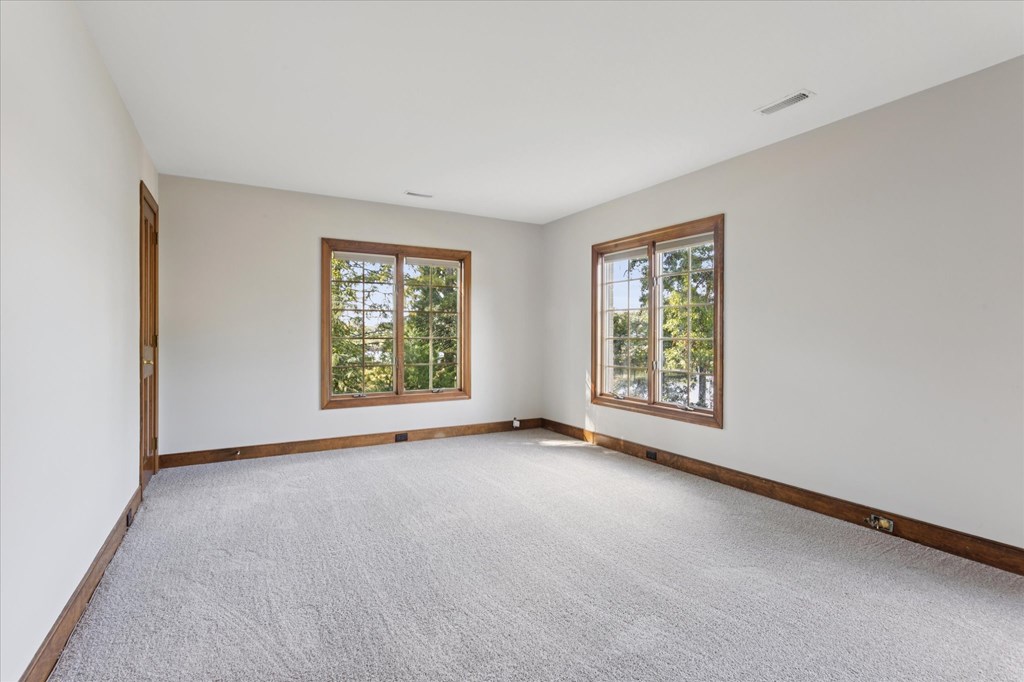 A room with a carpeted floor and two windows.