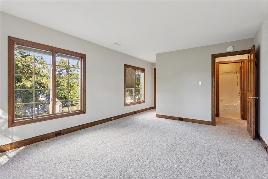 A room with a carpeted floor, a door, and a window.