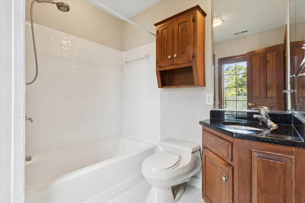 A white tiled bathroom with a white toilet and a white bathtub.