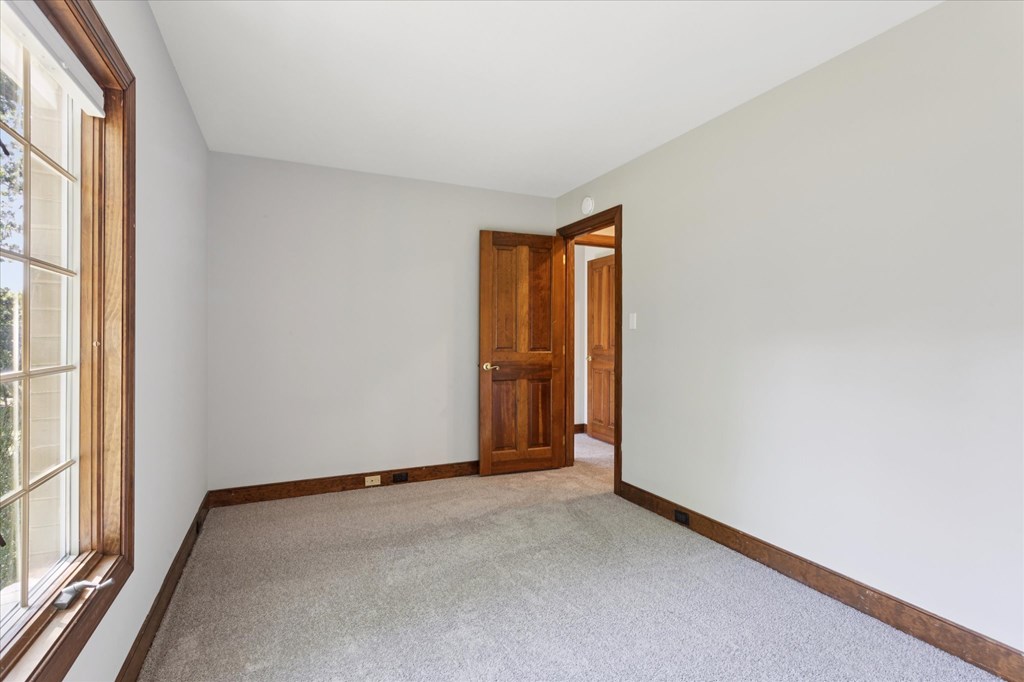 A room with a carpeted floor and a wooden door.