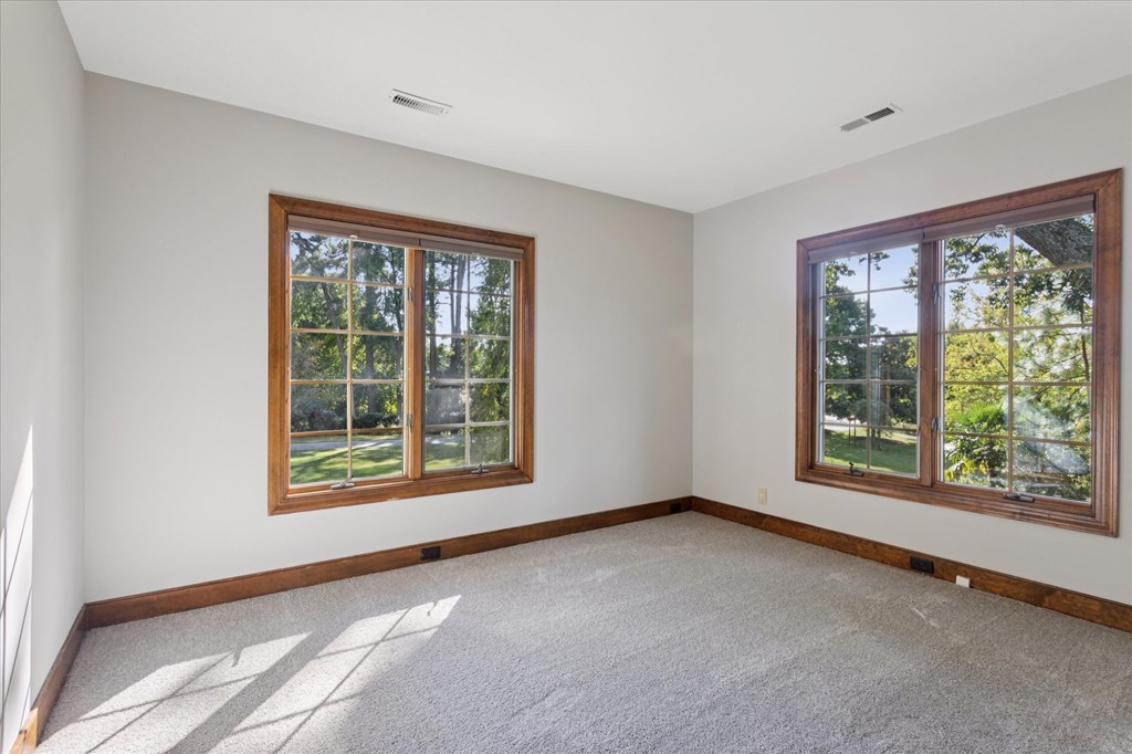 A room with two windows and carpeted floor.