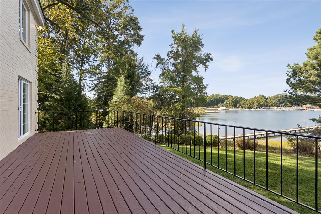 A wooden deck overlooks a lake surrounded by trees.