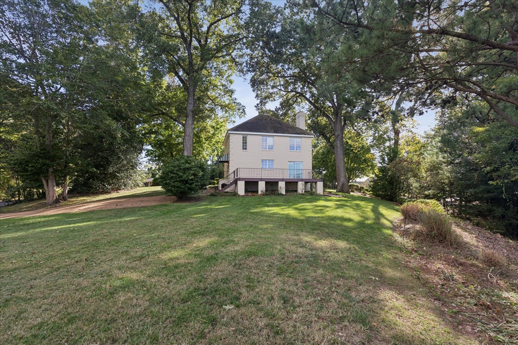A house is surrounded by trees in a grassy area.