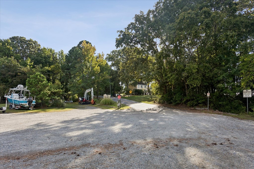 A gravel road with a boat and trees on the side.