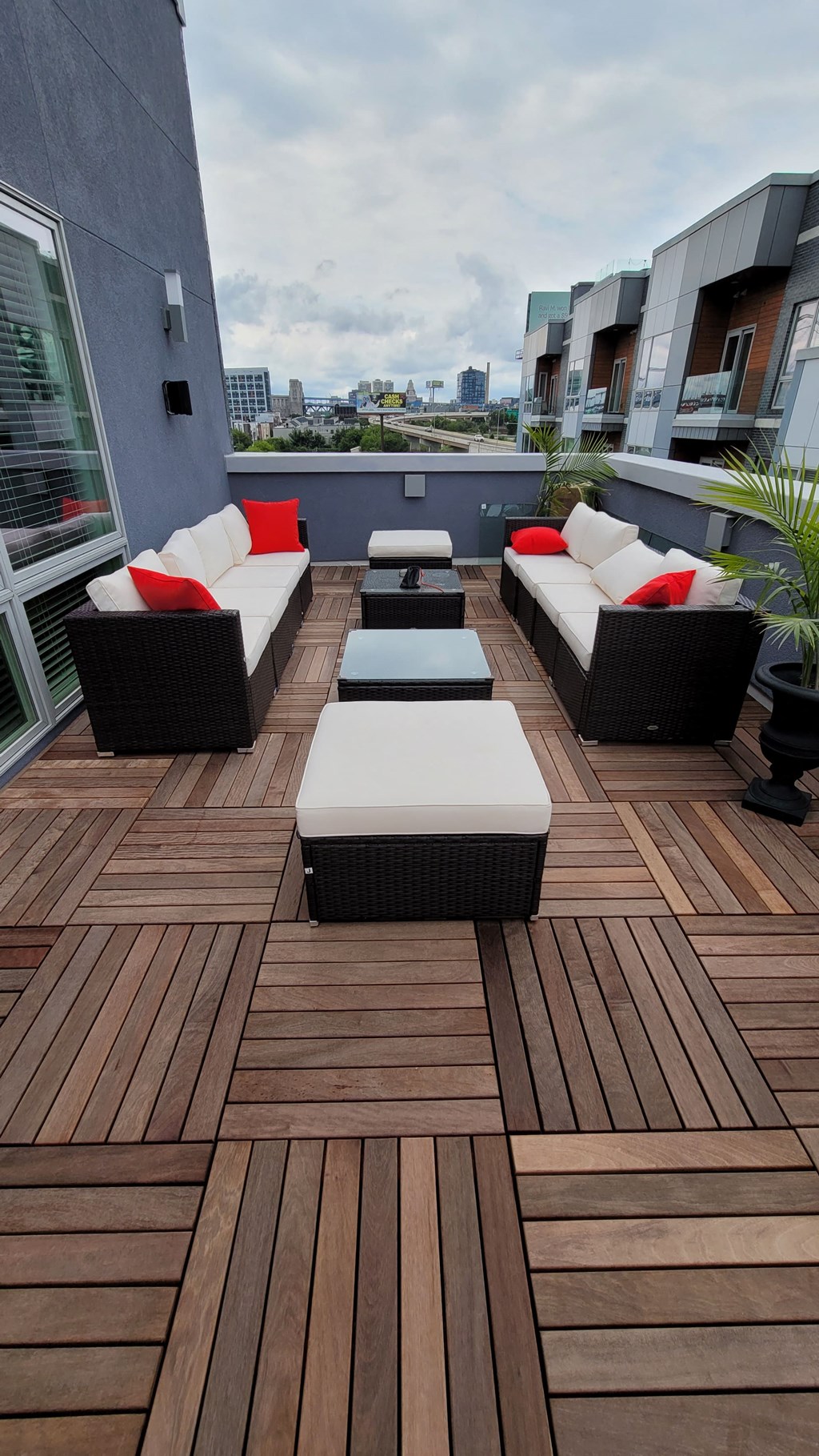 a rooftop deck with furniture and a city in the background