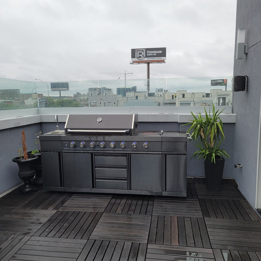 a stainless steel grill on a rooftop patio with a potted plant