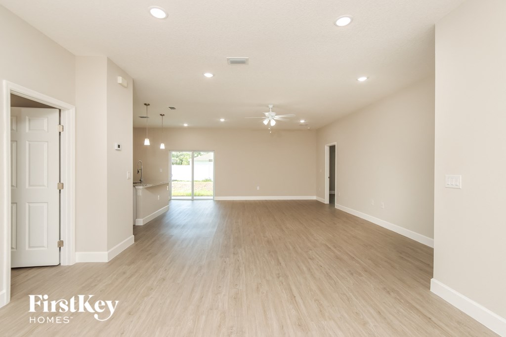 a spacious living room with white walls and wood flooring