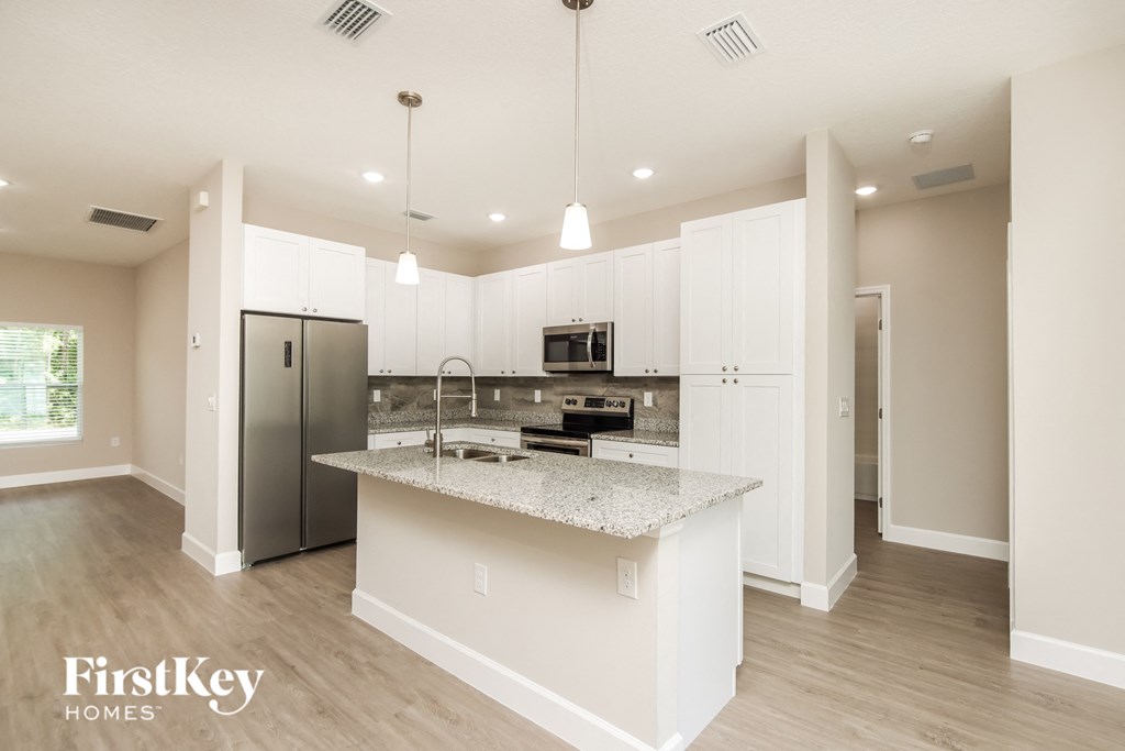 a kitchen with white cabinets and a marble counter top