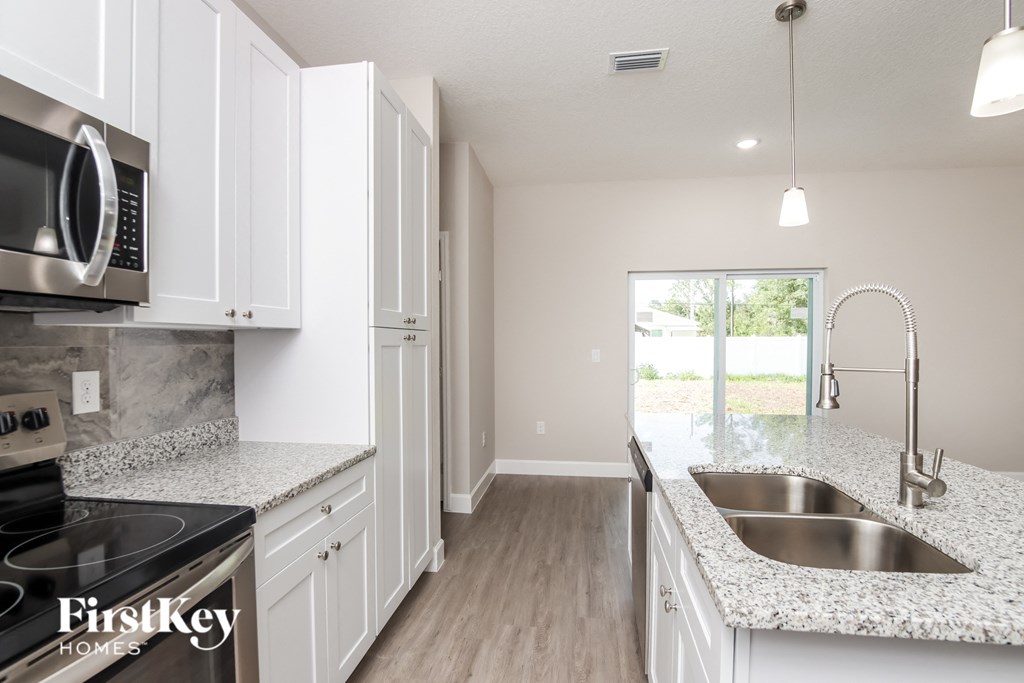 a kitchen with white cabinets and granite counter tops and a sink