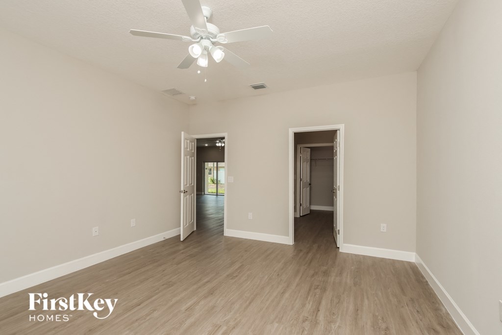 a spacious living room with white walls and a ceiling fan
