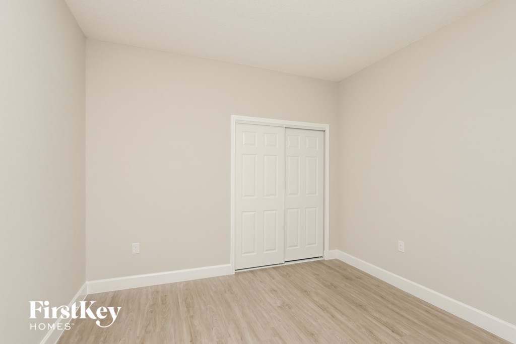 a bedroom with a white door and wood floors