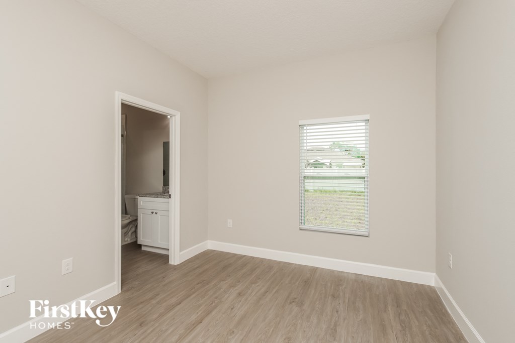 a bedroom with a door to a bathroom and a window