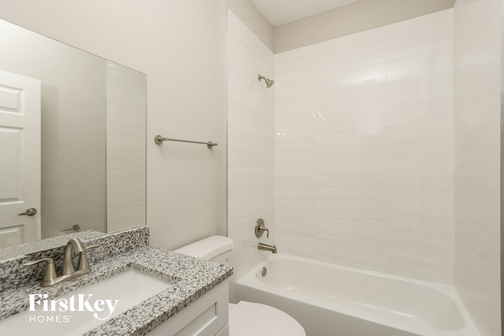 a white bathroom with a tub and a sink and a toilet