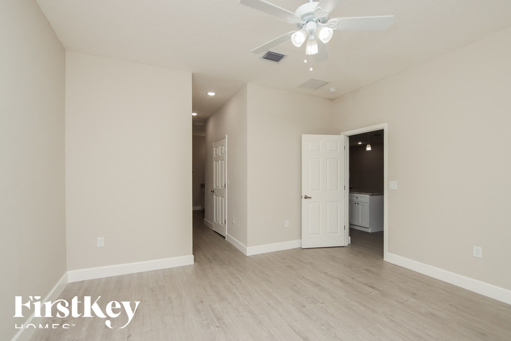 A spacious room with a ceiling fan and lighting fixture.