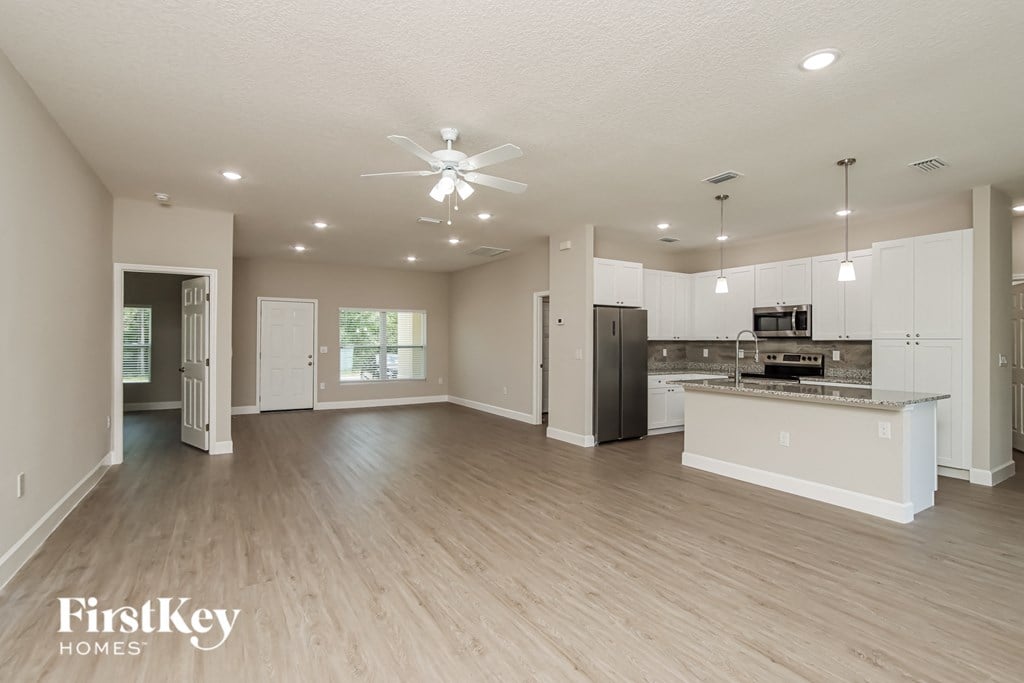 A spacious kitchen and living room with wooden floors and white walls.