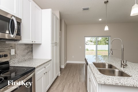 A kitchen with white cabinets and a granite countertop.