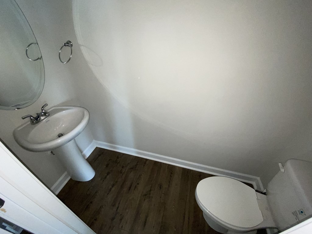A white toilet sits in a small bathroom next to a sink.
