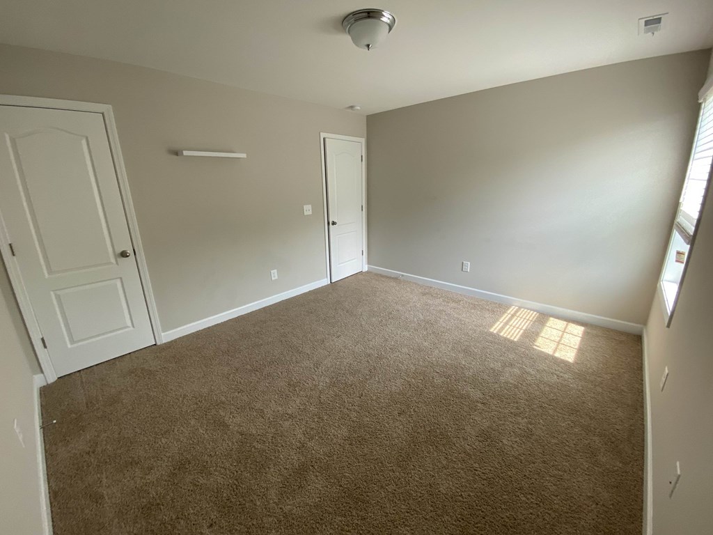 A room with carpeted floor and two doors.