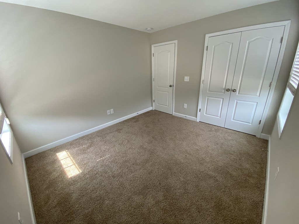 A room with a carpeted floor and two doors.