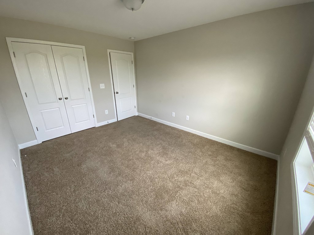 A room with carpeted floor and two white doors.