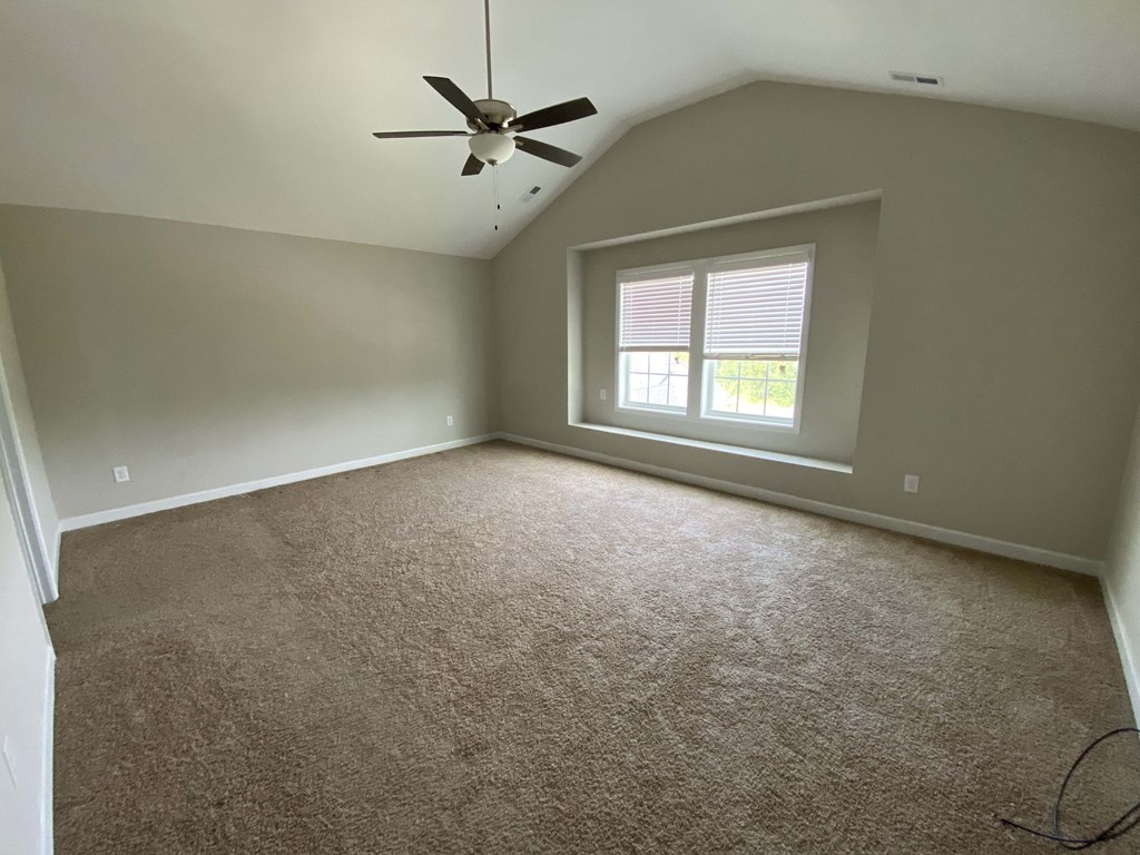 A room with a ceiling fan and carpeted floor.
