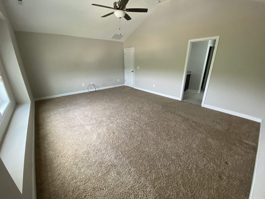 A room with a ceiling fan and carpeted floor.
