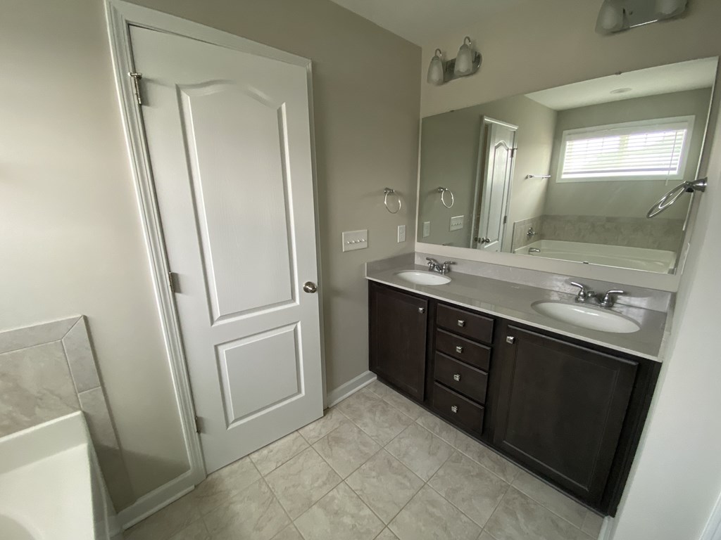 A bathroom with a white door, a sink, and a mirror.