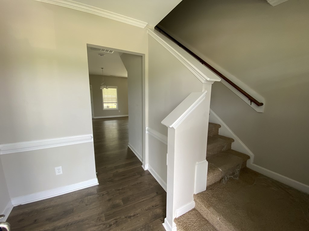 A staircase with a beige carpeted runner and white risers.